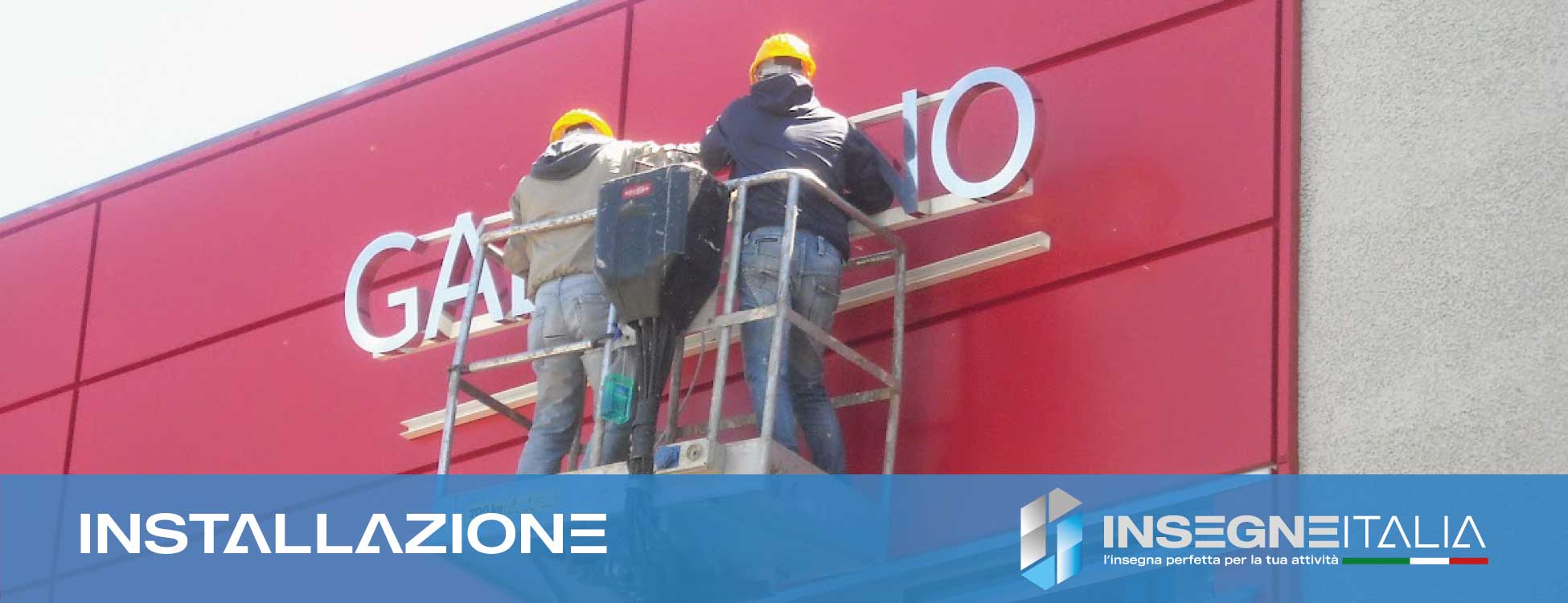 Foto di operai specializzati Insegne Italia durante la installazione di un allestimento pubblicitario sulla facciata di un negozio