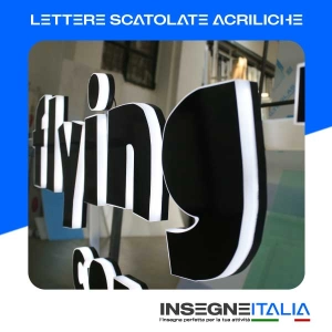 Lettere scatolate acriliche della scritta Flying Tiger Copenaghen, nere e retroilluminate, installate su vetro